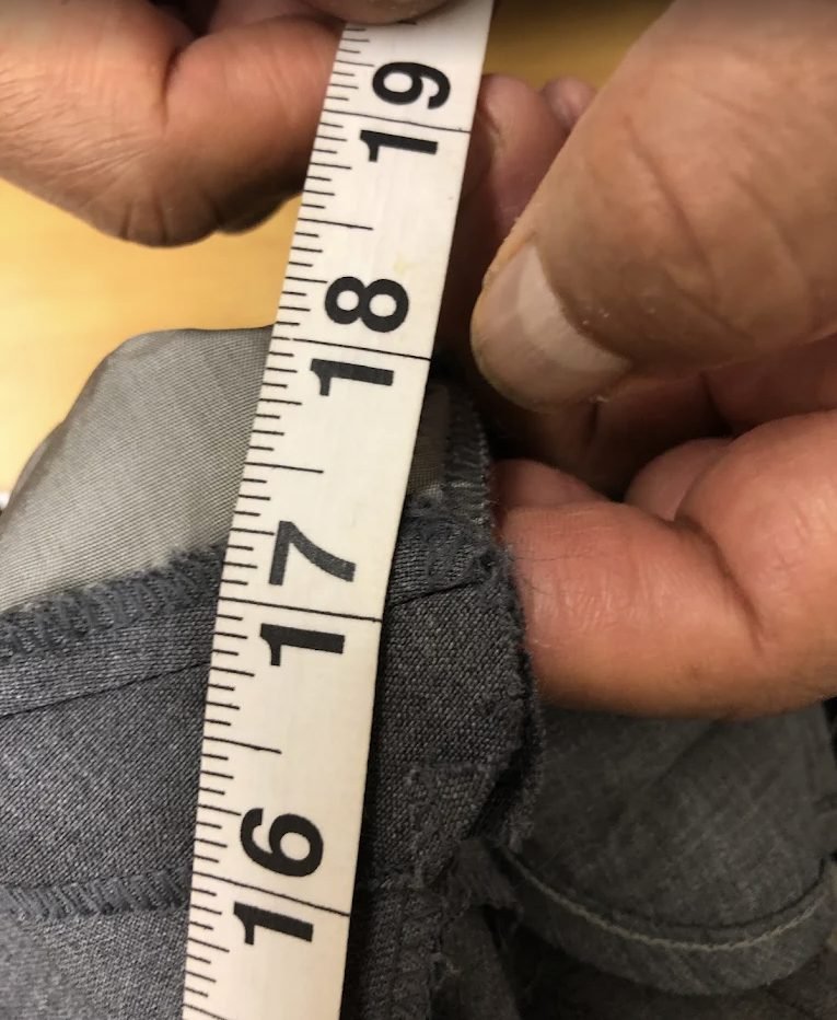 Tailor measuring a trouser waist with a tape measure
