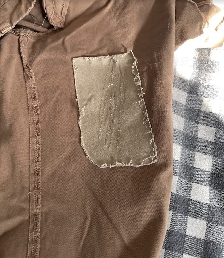 Hand-stitched patch repair on a canvas jacket